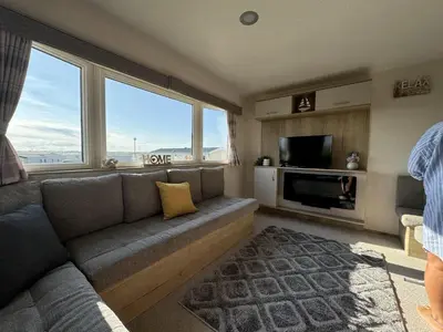 a living room with a couch and a large window at Perranporth Coastal Retreat- Sleeps8 in Perranporth