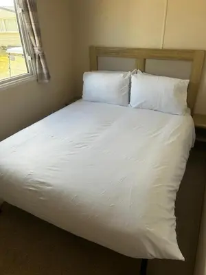 a bed with white sheets and pillows in a room at Perranporth Coastal Retreat- Sleeps8 in Perranporth