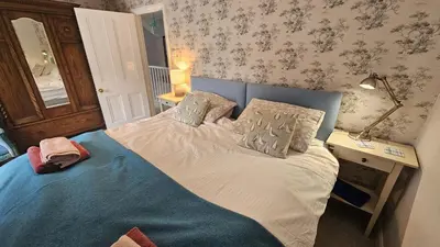 a bedroom with a bed with a blue head board at Glebe Barn in Ruan Lanihorne