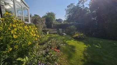 a garden with some flowers and a building at Glebe Barn in Ruan Lanihorne
