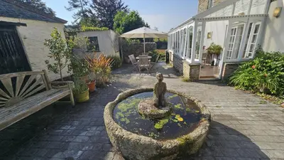 a statue of a woman in a fountain next to a building at Glebe Barn in Ruan Lanihorne
