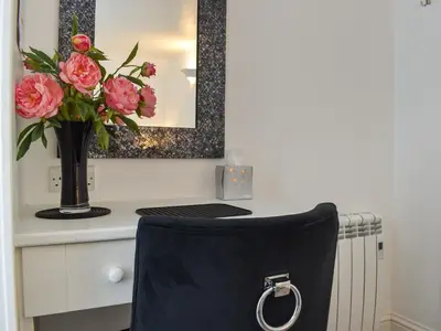 a vase of flowers on a desk with a vase of pink roses at Harbour Reach in Mevagissey