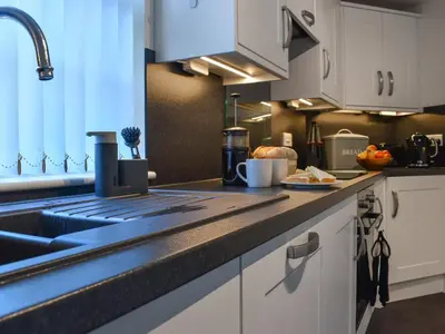 a kitchen with white cabinets and a sink at Harbour Reach in Mevagissey