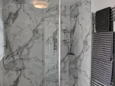 a bathroom with a marble shower with a glass door at Harbour Reach in Mevagissey