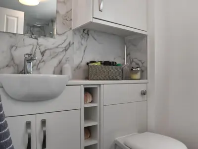 a white bathroom with a sink and a toilet at Harbour Reach in Mevagissey