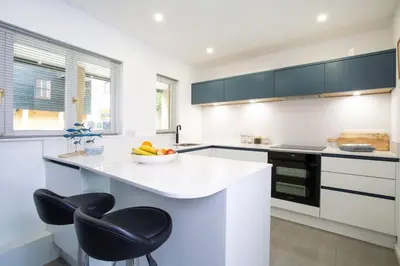 a white kitchen with a bowl of fruit on a counter at Janes Court, Packet Quays in Falmouth