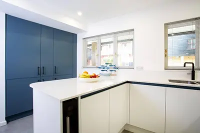 a kitchen with white cabinets and a bowl of fruit on the counter at Janes Court, Packet Quays in Falmouth