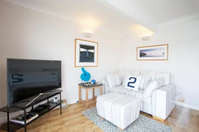 a living room with a white couch and a tv at Janes Court, Packet Quays in Falmouth