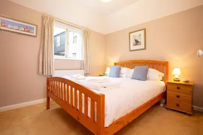a bedroom with a wooden bed and a window at Janes Court, Packet Quays in Falmouth