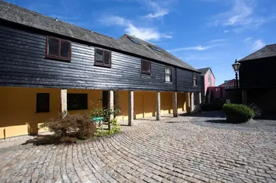 a large yellow building with a black roof at Janes Court, Packet Quays in Falmouth