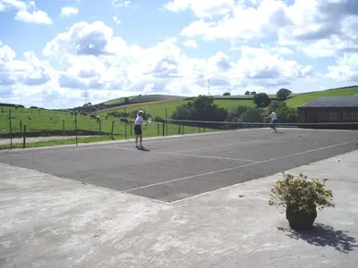 two people riding skateboards on a tennis court at Tregondale Manor Farm in Liskeard