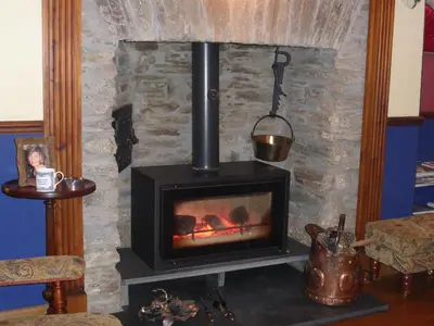 a stove in a room with a stone wall at Tregondale Manor Farm in Liskeard