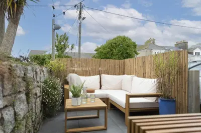 a patio with a white couch and a wooden fence at Offshore, Carbis Bay, St Ives in Carbis Bay