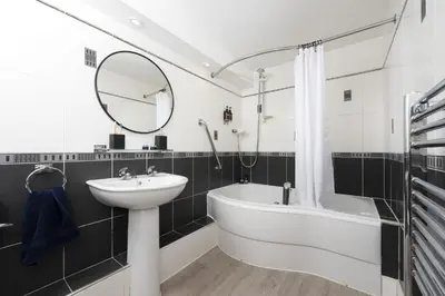 a bathroom with a sink and a tub and a mirror at Offshore, Carbis Bay, St Ives in Carbis Bay
