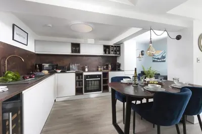 a kitchen with a wooden table and blue chairs at Offshore, Carbis Bay, St Ives in Carbis Bay