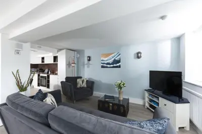 a living room with a couch and a tv at Offshore, Carbis Bay, St Ives in Carbis Bay