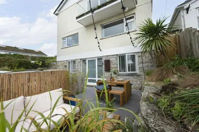 a patio with a table and chairs in front of a house at Offshore, Carbis Bay, St Ives in Carbis Bay