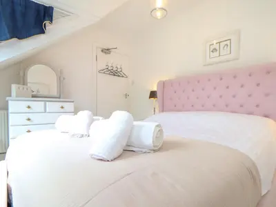 a bedroom with two beds with white sheets and a pink headboard at Mor Kernow in St Ives