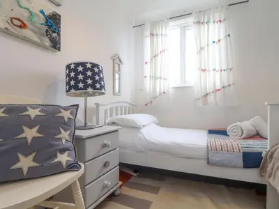a small bedroom with a bed and a dresser at Mor Kernow in St Ives