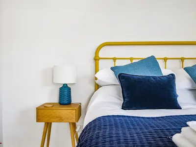 a bed with blue pillows and a lamp on a night stand at Fairwinds in Portreath