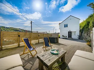a patio with two chairs and a table on a deck at Fairwinds in Portreath