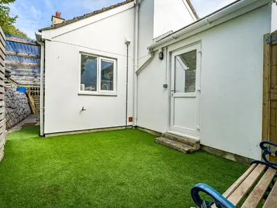 a white house with a yard with a bench at Fairwinds in Portreath