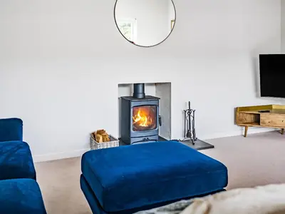 a living room with a blue couch and a fireplace at Fairwinds in Portreath