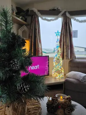 a living room with a christmas tree and a tv at Summer Breeze in Perranzabuloe