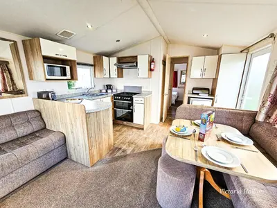 a living room with a couch and a table in a caravan at Summer Breeze in Perranzabuloe