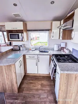 a kitchen with white cabinets and a stove top oven at Summer Breeze in Perranzabuloe