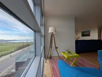 a living room with a large window with a view at Modern Apartment By The Beach in Newquay