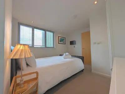 a bedroom with a bed with a lamp and a window at Modern Apartment By The Beach in Newquay