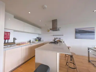 a kitchen with white cabinets and a counter top at Modern Apartment By The Beach in Newquay