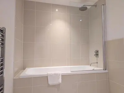 a bathroom with a bath tub with a shower at Modern Apartment By The Beach in Newquay