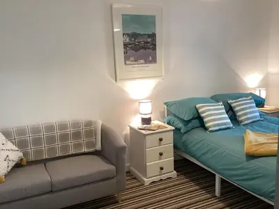 a bedroom with a bed and a couch and a lamp at Bluebirds villa in Padstow