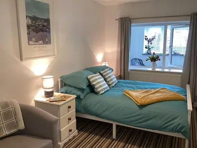 a bedroom with a bed and a chair and a window at Bluebirds villa in Padstow