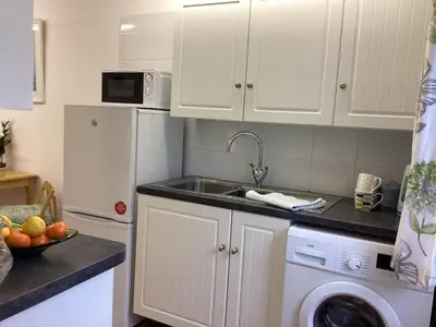 a kitchen with white cabinets and a sink and a dishwasher at Bluebirds villa in Padstow
