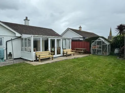 a house with a greenhouse and benches in a yard at Itldo in Truro