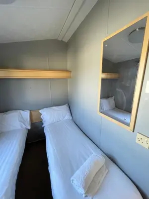 a small room with two beds and a mirror at Newquay Bay Holiday Resort Caravan 142 in Porth