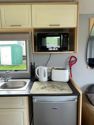 a kitchen with a sink and a microwave at Newquay Bay Holiday Resort Caravan 142 in Porth