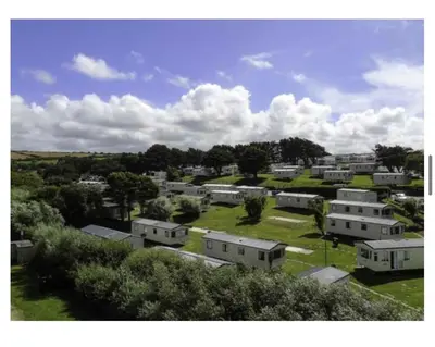 a group of houses in a field with trees at Newquay Bay Holiday Resort Caravan 142 in Porth