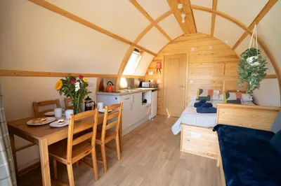 a room with a dining table and a bedroom at Grassington Farm by Wigwam Holidays in Helston