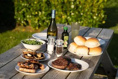 a wooden table with plates of food and bottles of wine at Grassington Farm by Wigwam Holidays in Helston