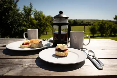 two plates of food on a wooden table with coffee at Grassington Farm by Wigwam Holidays in Helston
