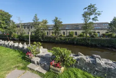 a building next to a river with flowers in pots at The Old Carriage Works in Lostwithiel