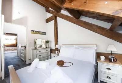 a bedroom with a white bed and wooden ceilings at The Old Carriage Works in Lostwithiel
