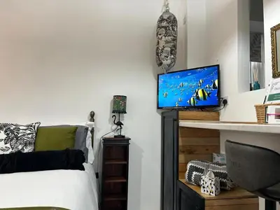 a bedroom with a bed and a tv on a wall at Thea Cottage in Perranuthnoe