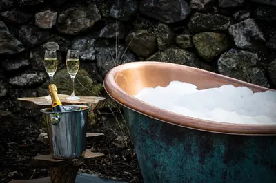 two glasses of champagne in a tub with two champagne glasses at POD St Ives - LUXURY GLAMPING ACCOMMODATION in St Ives