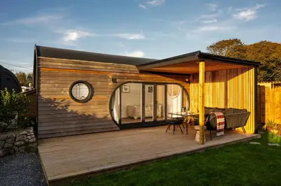 a small house with a deck with a table at POD St Ives - LUXURY GLAMPING ACCOMMODATION in St Ives