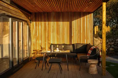 a patio with a couch and a table on a deck at POD St Ives - LUXURY GLAMPING ACCOMMODATION in St Ives